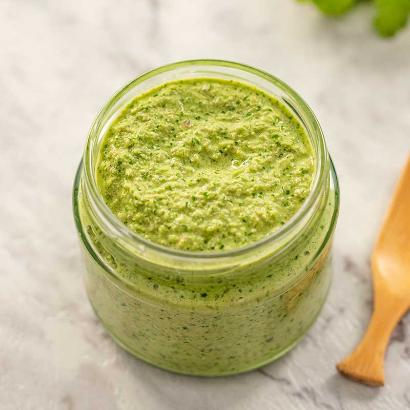 Image of keto thai green curry paste in a glass jar with a white background